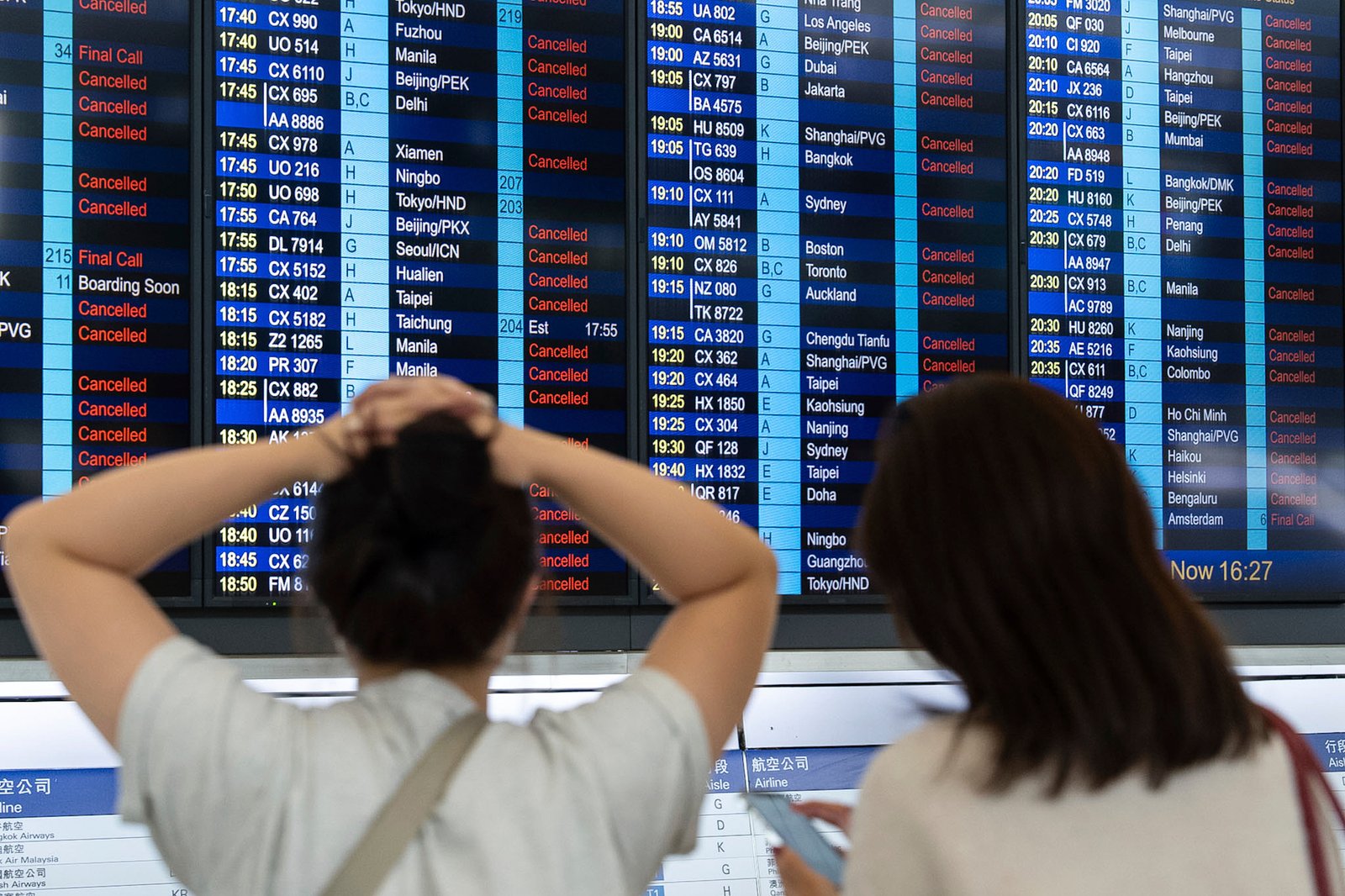 Passengers look at an information demonstration board showing canceled flights