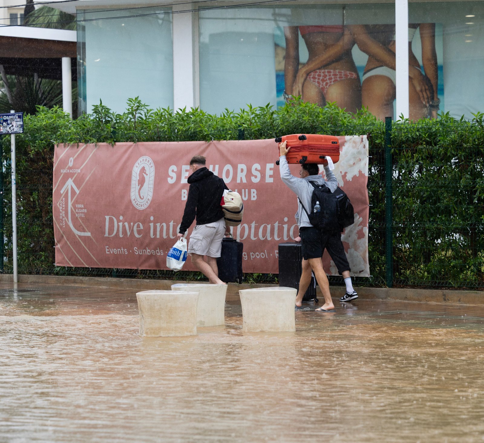 Tourists run through a flooded road in Ibisa on 30 September, 2025