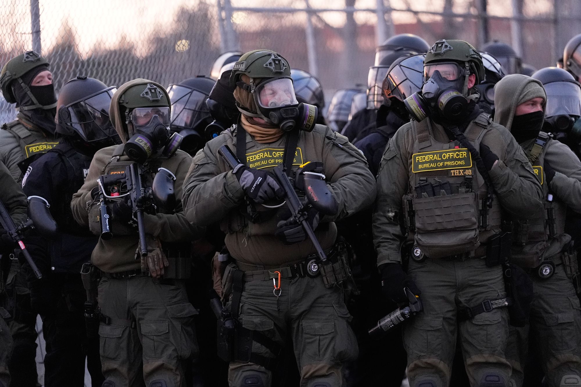 Federal agents stand guard outside a building in Minneapolis on Saturday as protests continue over the city's shooting death of Renee Goode