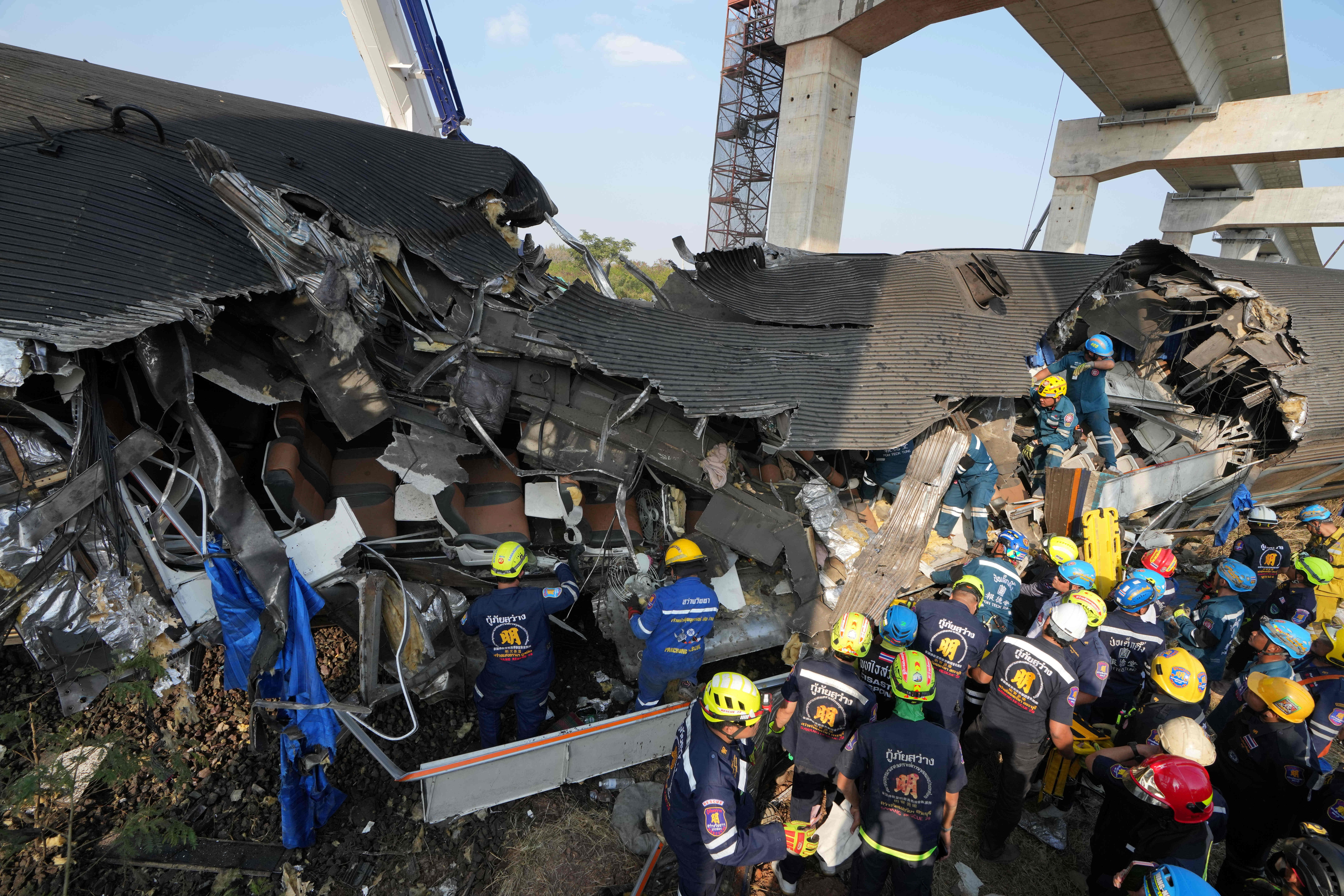Rescue workers work among the rubble after a construction crane crashed into a passenger train in Nakhon Ratchasima province
