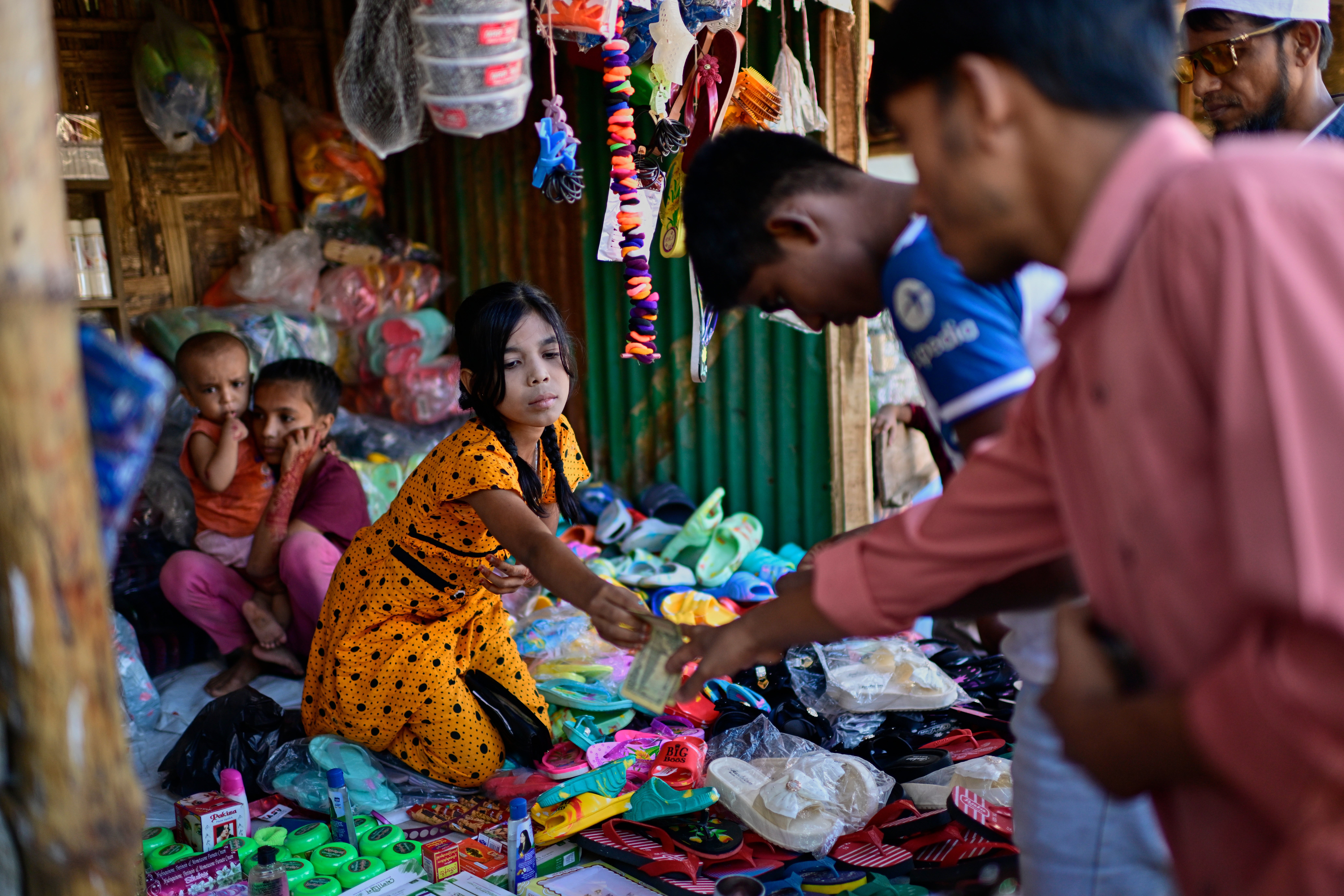 A Rohingya girl sells goods at her stall in a refugee camp in Cox's Bazar, Bangladesh, on November 21, 2025
