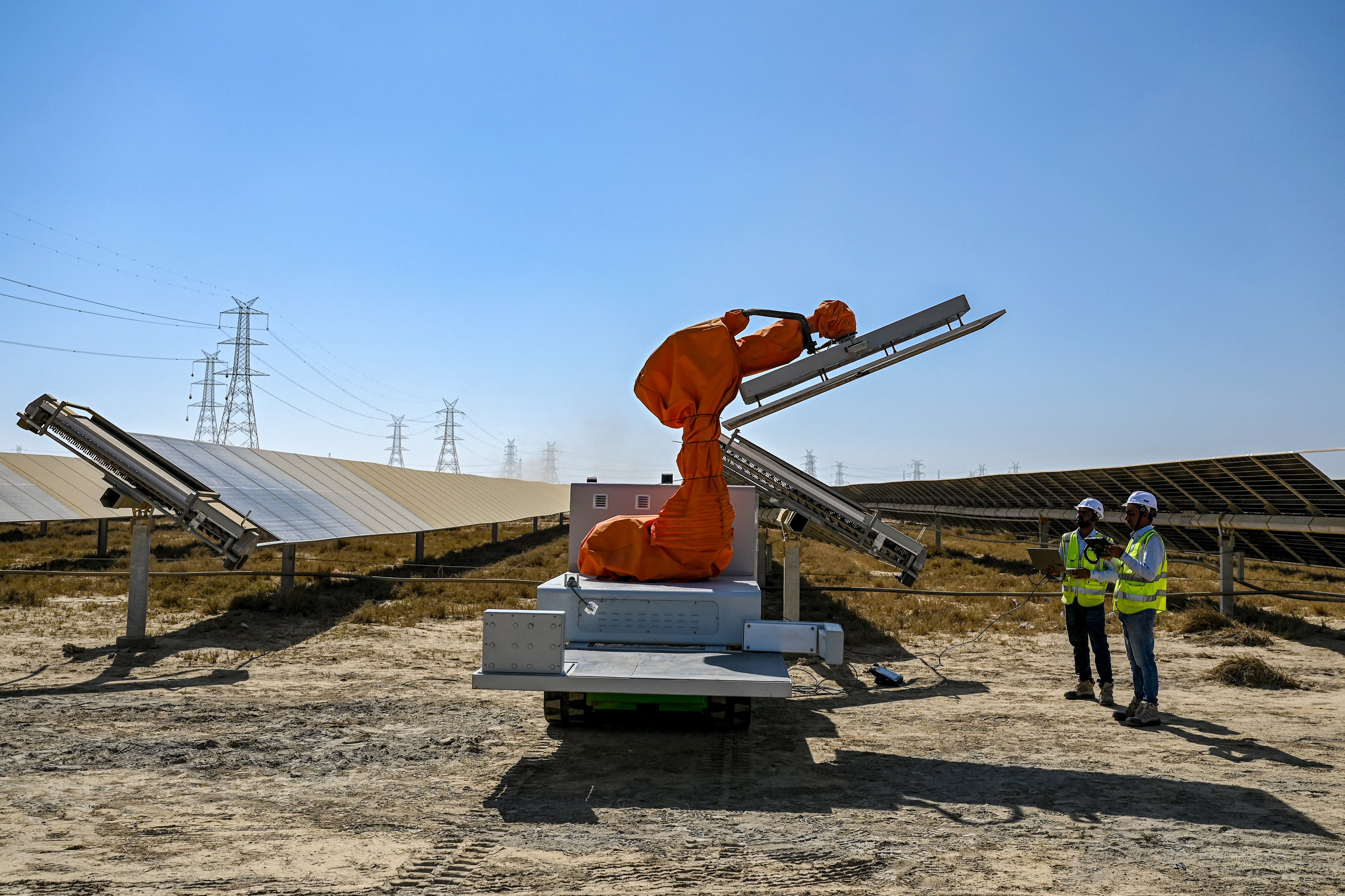 Workers operate machinery during the installation of solar panels at Adani Group's Kafuda Renewable Energy Park