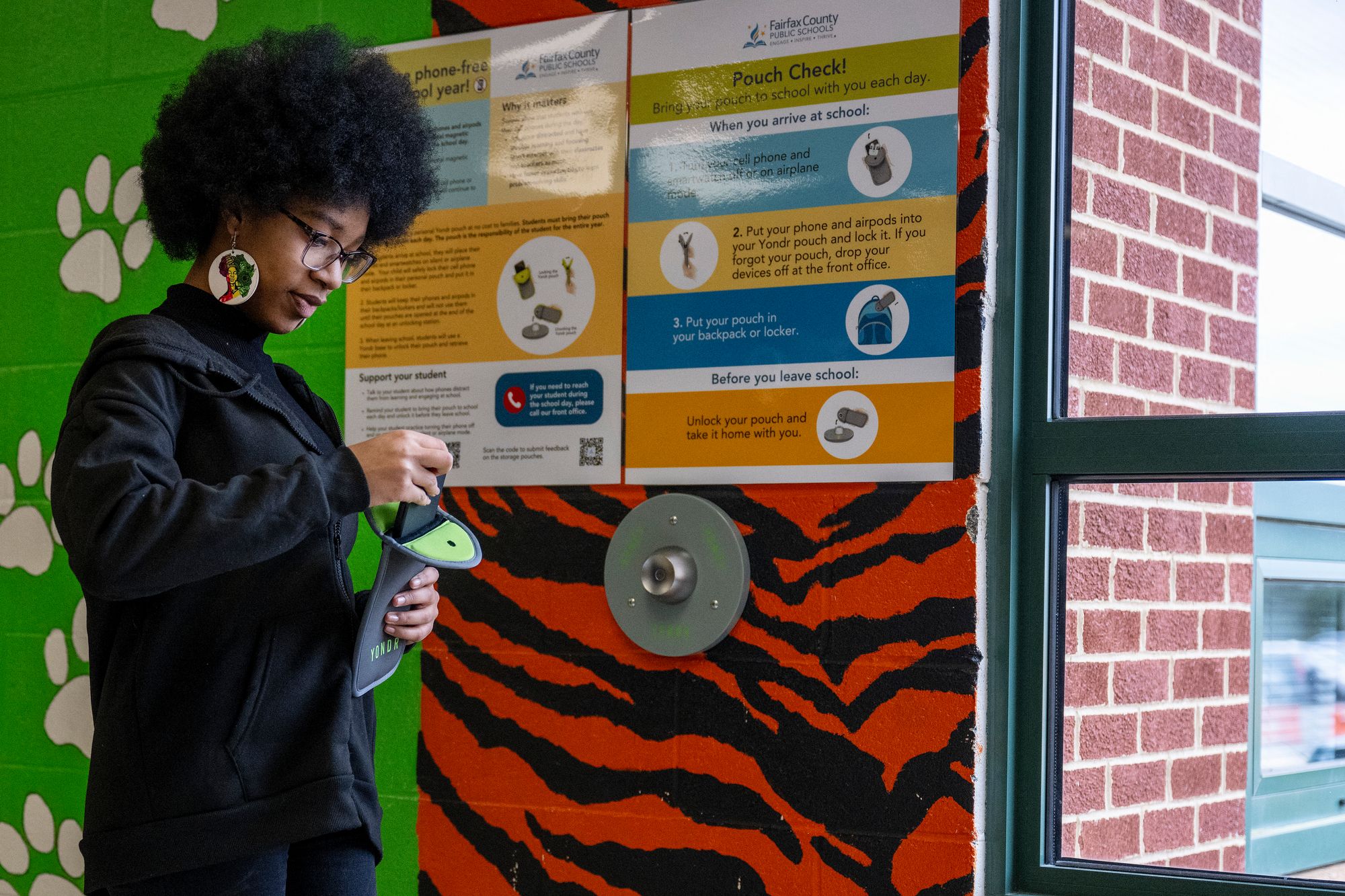 Ja' Nae Dorsey, an eighth-grader at Mark Twain Middle School in Alexandria, Virginia, takes her phone out of a lockable storage bag after the school bell rings, one of many schools in the U.S. and around the world to implement personal device bans