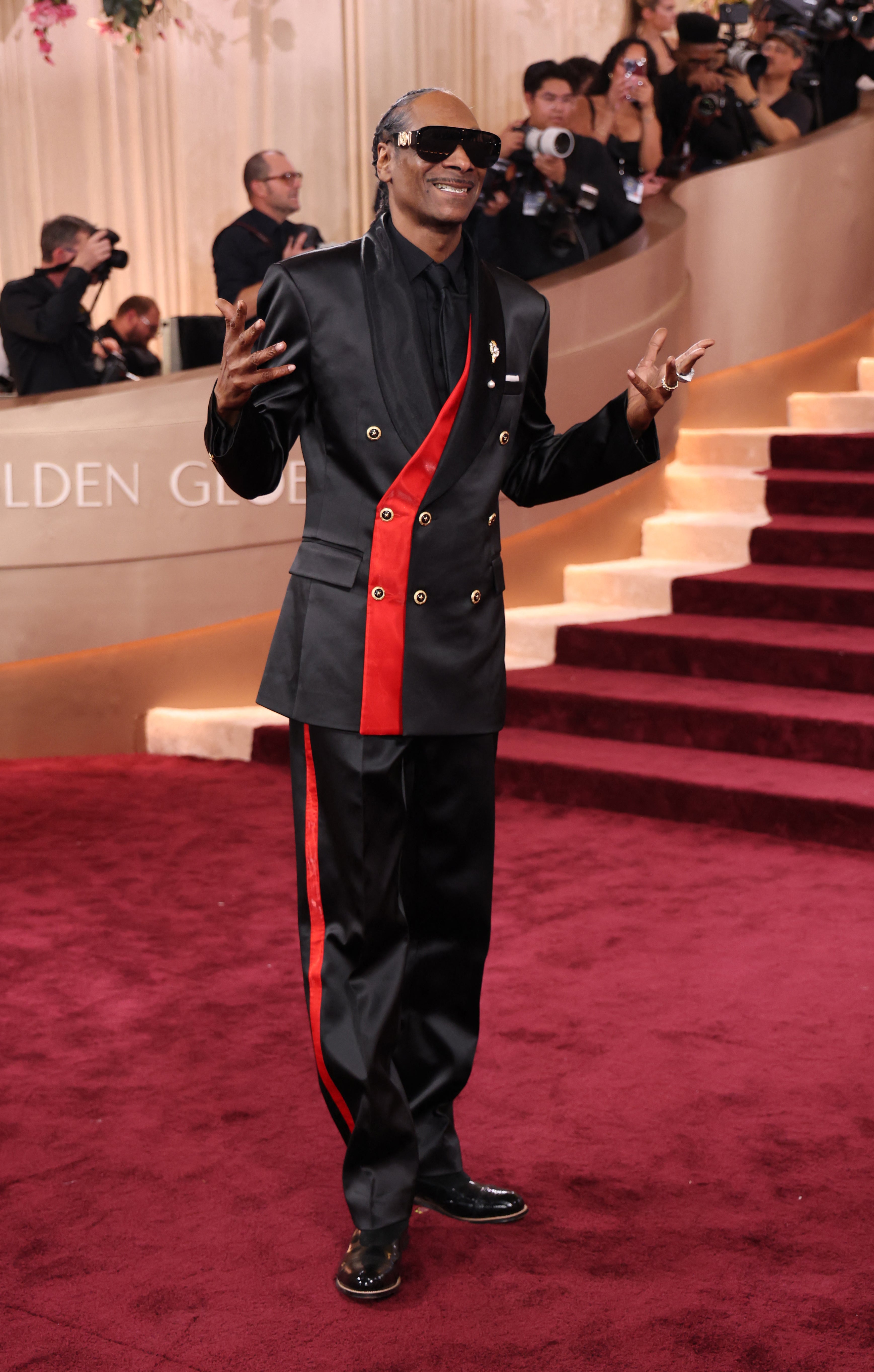 Snoop Dogg wanted more than just a tux, opting for a black jacket with red stripes and gold buttons, and matching pants. He completed his all-black ensemble with sunglasses and a tie