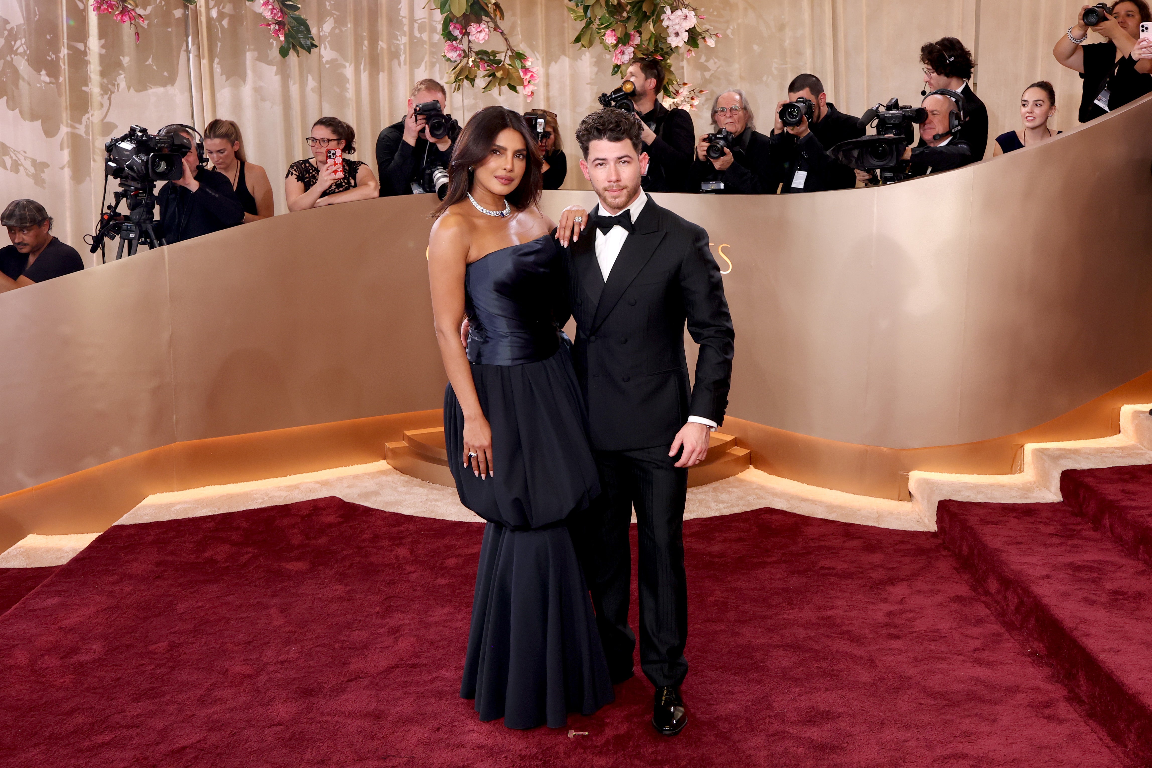 Singer Nick Jonas looked timeless in a classic black tuxedo and matching bow tie. He posed next to wife Priyanka Chopra, who wore a stunning navy blue dress with a ruffled skirt and diamond necklace