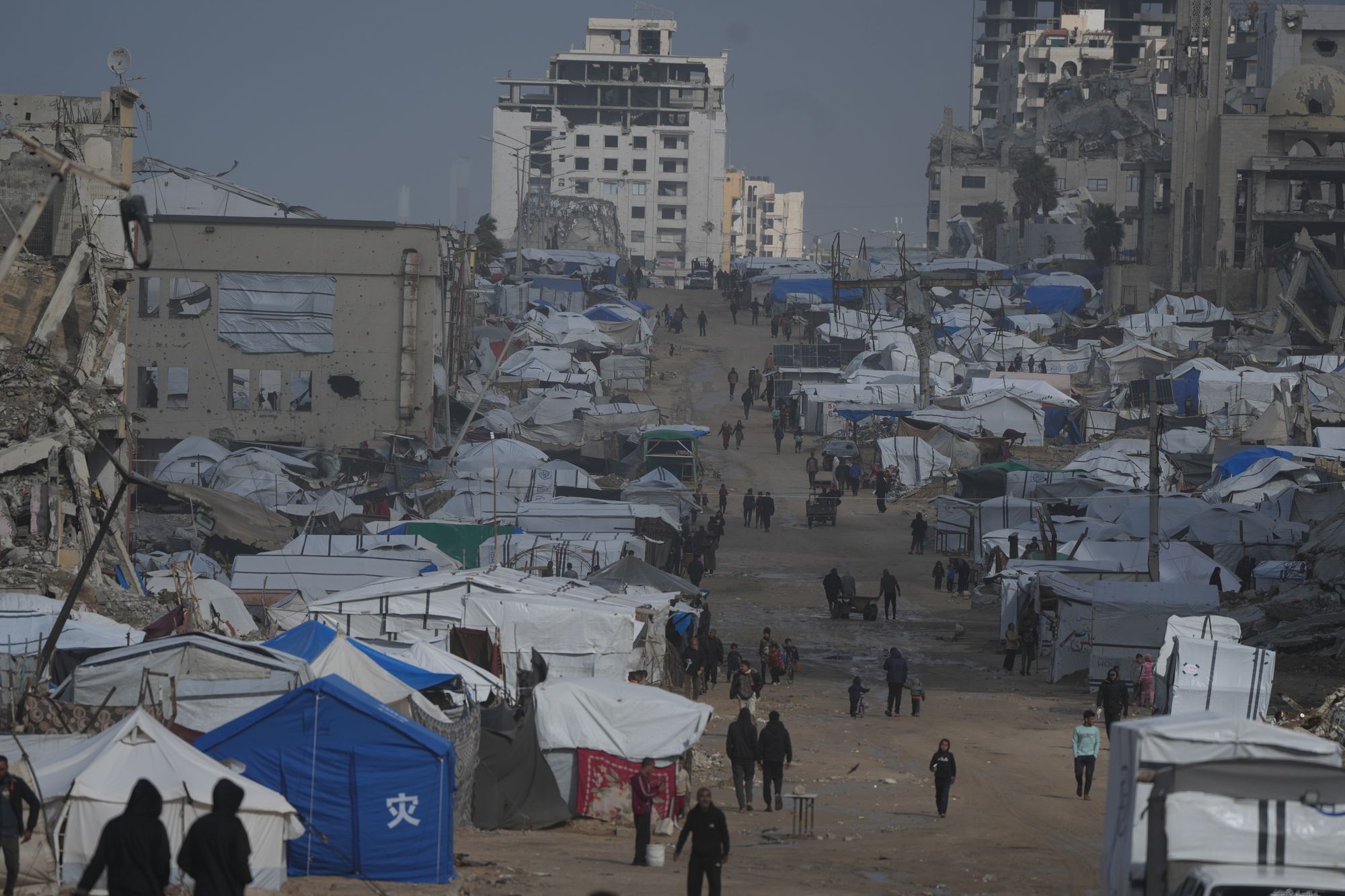 Palestinians walk along a street of damaged buildings in Gaza City
