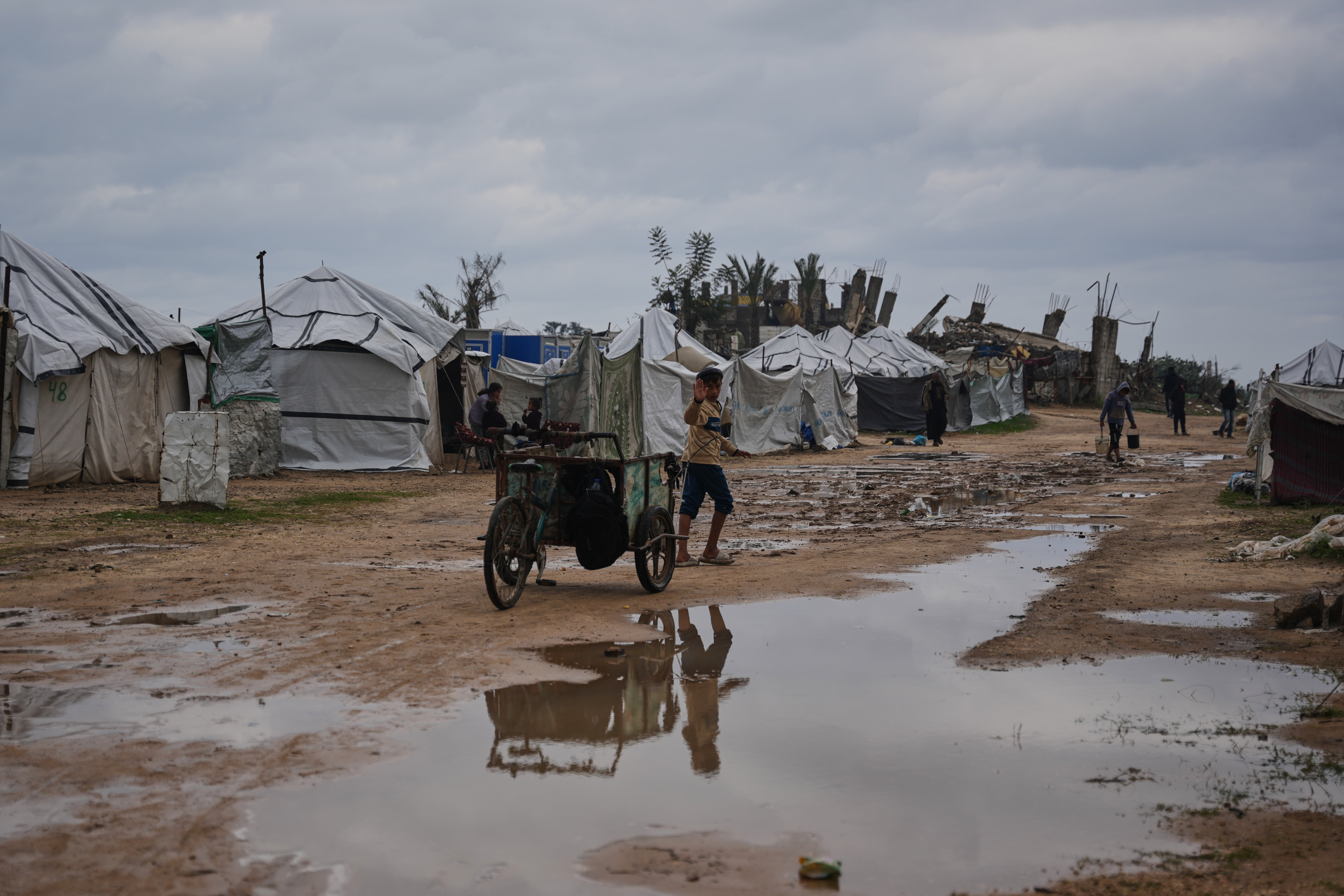 A child walks in a tent camp for displaced Palestinians after heavy rains in Nouserat, Gaza