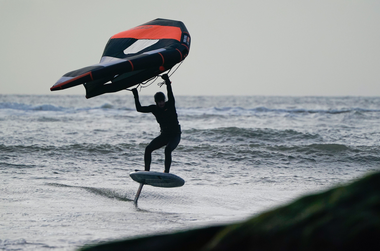 A man windsurfing in the sea near Avon Beach in Mudeford, Dorset