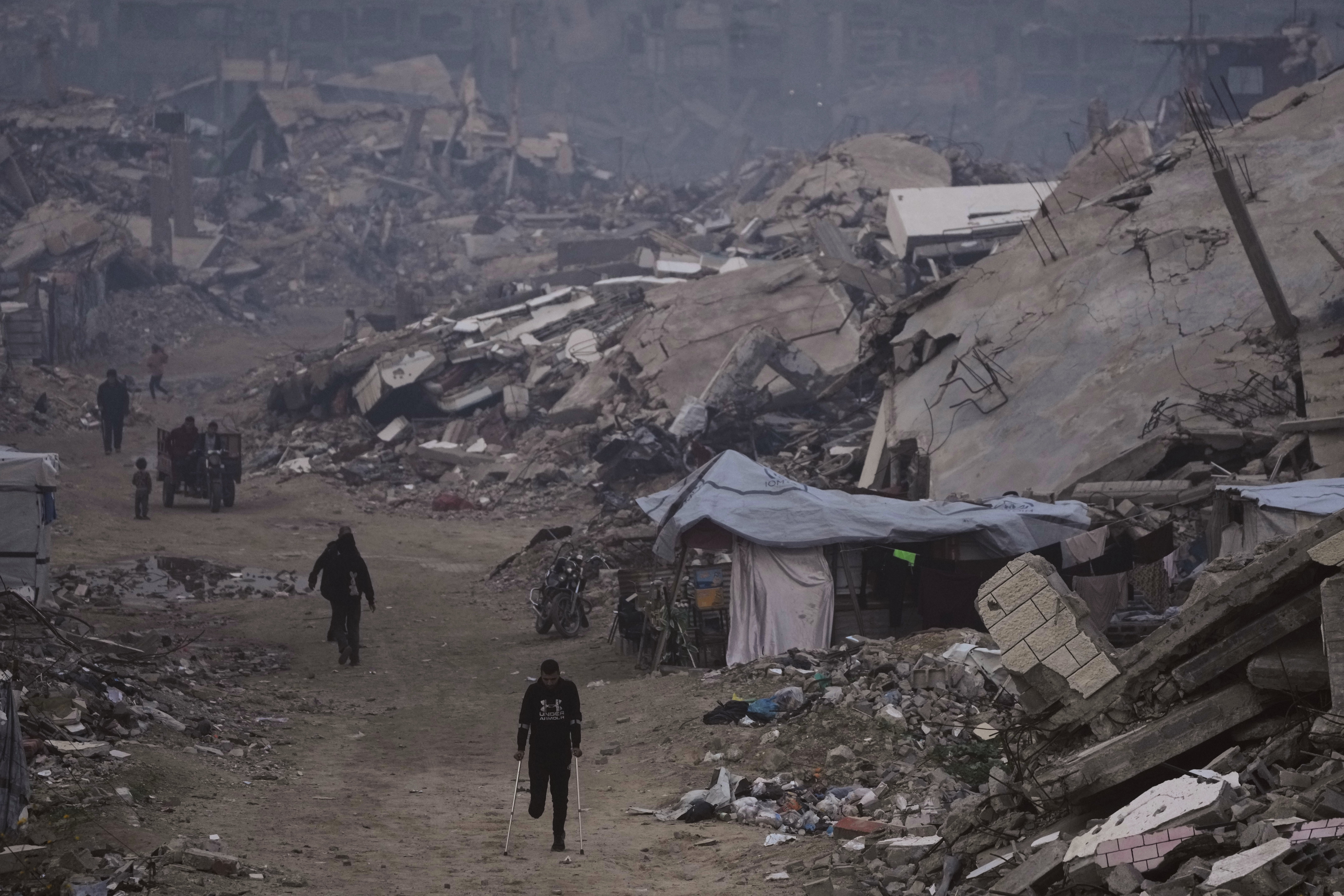 Palestinians walk past the ruins of destroyed buildings in Gaza City on January 4, 2026