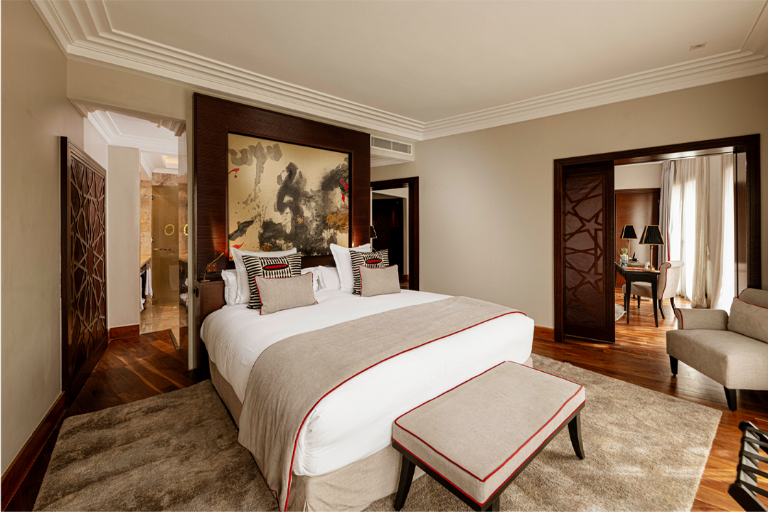 The bedroom has a minimalist style with abstract artwork, wood and neutral furniture